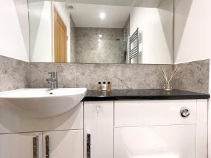 a white bathroom with a sink and a mirror at Luxurious Apartment Just Off Mill Rd in Cambridge