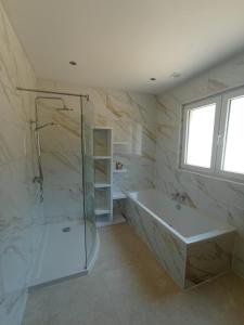 a bathroom with a tub and a glass shower at La Villa les pieds dans leau in Comblain-au-Pont