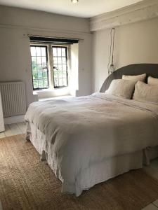 a large white bed in a bedroom with a window at Charming Grade 2 listed building in Wiltshire in Melksham