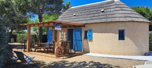 a small house with a thatched roof and a table at Barcarès joli mas de pêcheurs rénové classé 4 étoiles 8 couchages in Le Barcarès
