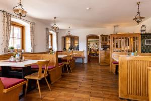ザウルグルプにあるGasthof zur Post Saulgrubのテーブルと椅子が備わるウッドフロアのレストランを併設しています。