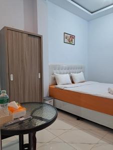 Habitación pequeña con 2 camas y mesa. en Guguak Puro Guest House en Padangpanjang