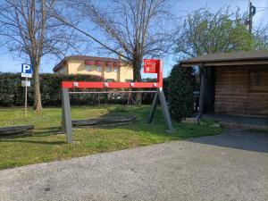 Codevigo的住宿－巴拉布斯卡客房旅館，坐在建筑物旁边的草上的一个红色长凳