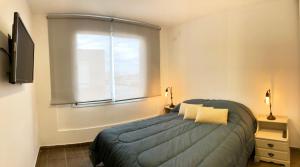 a bedroom with a blue bed and a window at RIO 5 Departamento temporario in Villa María