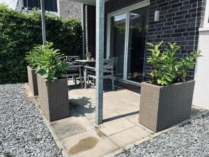 a patio with a table and two potted plants at FeWo Am Ring Neubau & Terrasse in Nordhorn