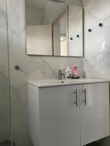 ein weißes Badezimmer mit einem Waschbecken und einem Spiegel in der Unterkunft roofgarden apartment close subway station in Athen