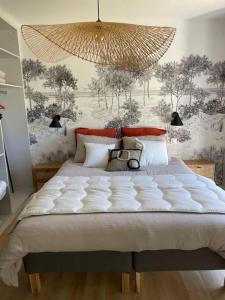 ein Schlafzimmer mit einem großen weißen Bett und einem Kronleuchter in der Unterkunft Charmante longère à 700 m de la plage in Guidel