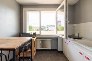 eine Küche mit einem Tisch und einem großen Fenster in der Unterkunft Appart'hotel de Montplaisir in Saint-Étienne