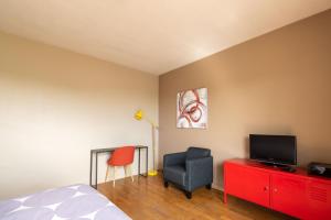 - une chambre avec un lit, une télévision et une chaise dans l'établissement Appart'hotel de Montplaisir, à Saint-Étienne