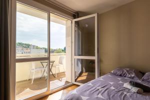 a bedroom with a bed and a view of a balcony at Appart'hotel de Montplaisir in Saint-Étienne