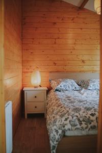a bedroom with a bed and a lamp on a night stand at Chalet 2 chambres parking, à 5 min à pieds d'Etretat in Bordeaux-Saint-Clair