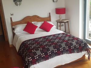 a bedroom with a bed with red pillows on it at Powis Cottage in Laugharne