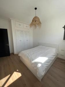 um quarto branco com uma cama e um lustre em Bel Appartement Agadir Tamourit em Agadir