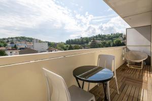 a balcony with a table and chairs and a view at Appart'hotel de Montplaisir in Saint-Étienne