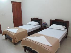 2 camas en una habitación de hotel con paredes blancas en Phoenix Serviced Apartment - Anna Nagar en Chennai
