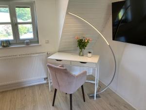 a desk with a vase of flowers and a chair at Balance Apartments by M&A - Ferienwohnung Dohrenbach in Witzenhausen