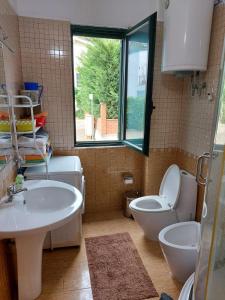 a bathroom with a sink and a toilet and a window at Shtepia e luleve in Golem