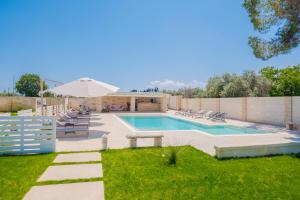 una piscina con sedie e ombrellone in un cortile di Villa Malea Luxury - Otranto a Giuggianello