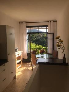 a kitchen with a table and a dining room with a window at Maison Blanche in Laroque-des-Albères