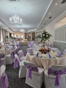 um salão de banquetes com mesas brancas e cadeiras roxas em Pensiunea Moldova em Piatra Neamţ