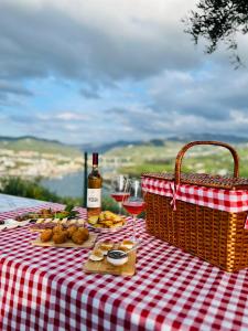 een picknicktafel met een fles wijn en een mand met eten bij Quinta Pecêga - AL in Peso da Régua