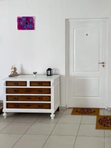 a white room with a dresser and a white door at Tanyacsárda Panzió in Baja