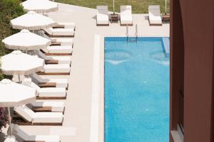 an overhead view of a swimming pool with lounge chairs and umbrellas at ĪKYMA Boutique in Polychrono