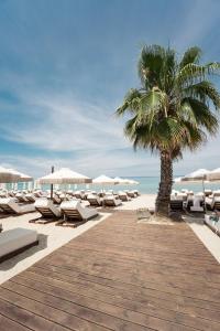 a row of lounge chairs and a palm tree on the beach at Ikyma Boutique in Polykhrono