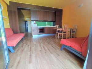 a living room with red couches and a kitchen at Soleil Apartmanok Balatonlelle in Balatonlelle