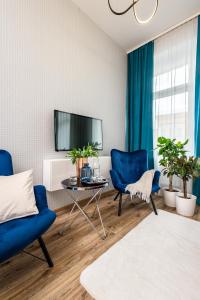 a living room with blue chairs and a tv at Hotel Sofia by The Railway Station Wroclaw in Wrocław