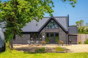 a home with a black roof and a house at The Barns at Green Valley Farm in Heveningham