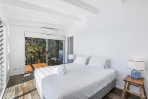 a white bedroom with a bed and a balcony at Kahala in Point Lookout +12 photos