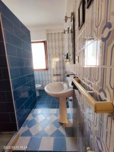 a bathroom with a sink and a blue tiled wall at Room in Apartment - La Palma King Room With Balcony in Cagliari