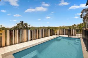a swimming pool in a backyard with a wooden fence at Kahala in Point Lookout