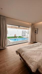 a bedroom with a large window with a swimming pool at شاليه الجبل in Ḑubā