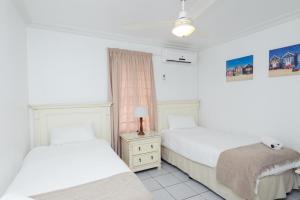 a bedroom with two beds and a night stand with a lamp at Le Paradis 5 - With Inverter in Ballito