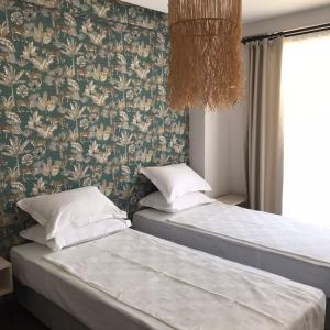 two beds in a room with floral wallpaper at Eva Otel Çeşme in Cesme