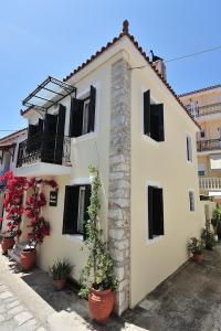 a white building with black windows and potted plants at Orestis Mansion Skiathos in Skiathos