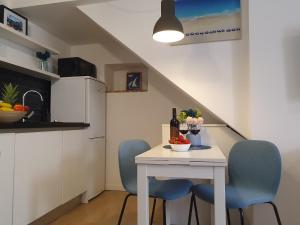 una pequeña cocina con una mesa blanca y sillas azules en Korado Studio Apartment en Vrsar