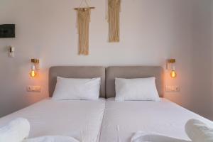 a bedroom with two beds with white sheets and lights at Eleftheria Studios in Antiparos