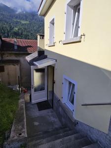 a white building with a door and some stairs at Airolo with private parking in Airolo