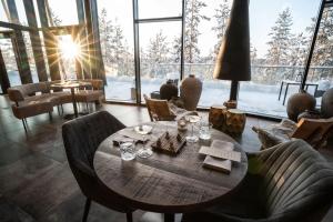 a dining room with a table and chairs with the sun shining at Kuru Resort in Rantasalmi