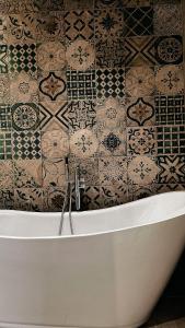 a bath tub in a bathroom with a tiled wall at شاليه الجبل in Ḑubā