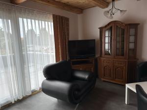 ein Wohnzimmer mit einem schwarzen Stuhl und einem TV in der Unterkunft 1852 Landgasthof- Ferienwohnung in Elze
