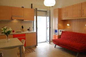 ein Wohnzimmer mit einem roten Sofa und eine Küche in der Unterkunft Residence Helene in Tortoreto Lido