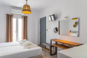 a bedroom with two beds and a table and a mirror at Eleftheria Studios in Antiparos +17 photos