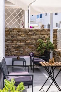 a patio with chairs and tables and a stone wall at Eleftheria Studios in Antiparos