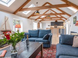 una sala de estar con sofás azules y una mesa. en Swallows Barn, en Totnes