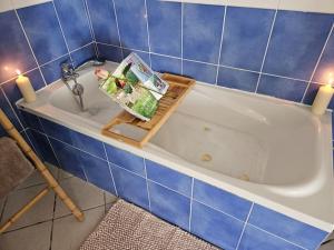 baño de azulejos azules con bañera y revista en Gite Le haut du Caraquet, en Desvres