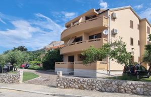 a building with a stone wall in front of it at Apartments Barbalic D in Baška